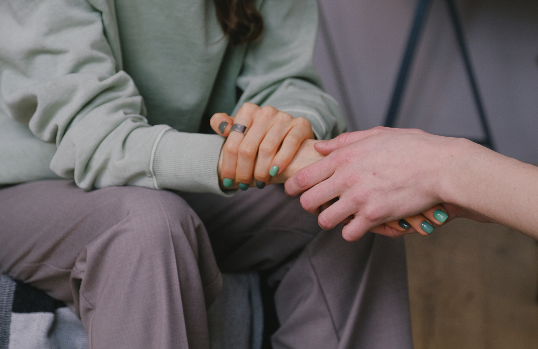 holding hands in support whilst sitting down