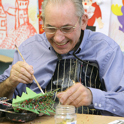 Older male smiling whilst creating artwork